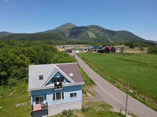 Discover this charming blue house nestled in a picturesque rural landscape, offering stunning mountain views.