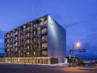 Experience modern luxury at this stunning hotel, featuring a striking architectural design with a concrete facade and warm wooden accents.