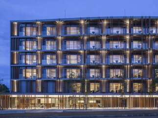 Experience modern living in this stunning multi-story building, featuring a unique facade with vertical wooden louvers and ample glass balconies.