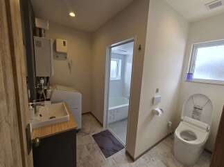 Discover this modern bathroom featuring a sleek vanity with a vessel sink, a convenient washing machine, and a separate bathtub area for ultimate relaxation.