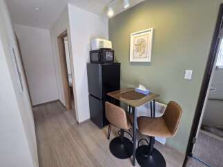 Discover this charming studio apartment featuring a compact kitchen area with a microwave and refrigerator, perfect for simple meal preparation.