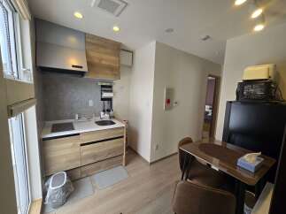 Discover this modern studio apartment featuring a compact yet functional kitchen with sleek cabinetry and a stainless steel range hood.