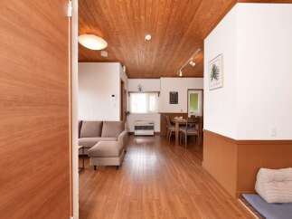 Step into this inviting living space featuring a comfortable sectional sofa and a warm, wood-paneled ceiling.