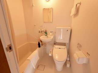 This compact bathroom features a bathtub, a sink, and a toilet with a bidet function, all designed for efficiency and comfort.