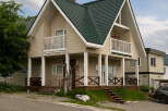Discover this charming two-story home featuring a distinctive dark green metal roof and a welcoming beige exterior.