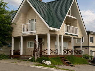 Discover this charming two-story home featuring a distinctive dark green metal roof and a welcoming beige exterior.