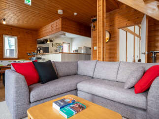 Experience cozy living in this charming wooden cabin, featuring a spacious sectional sofa perfect for relaxation.