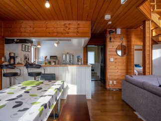 Experience cozy living in this charming wooden interior home, featuring a well-equipped kitchen with bar seating and a dining area perfect for gatherings.