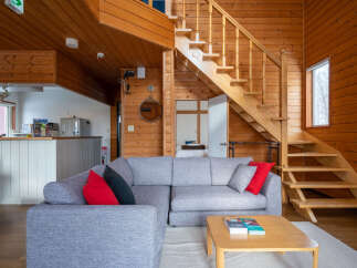 Experience cozy living in this charming wooden cabin, featuring a spacious sectional sofa perfect for relaxation.