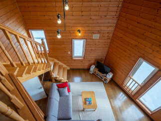 Experience cozy living in this charming wooden cabin featuring a spacious living area with a comfortable sectional sofa and a coffee table.