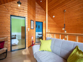 Experience cozy living in this charming wooden cabin, featuring a comfortable living area with a plush sofa and accent pillows.