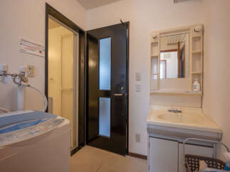 This compact bathroom features a washing machine and a separate shower area, perfect for efficient living.