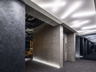 Experience modern luxury in this sophisticated lobby featuring raw concrete accents and dramatic linear lighting.