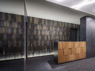 Experience a sophisticated reception area featuring a striking textured wall and a modern wooden reception desk.