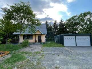 Discover this charming property featuring a cozy light yellow house with a welcoming porch and a dark brown door, complemented by a spacious two-car garage.