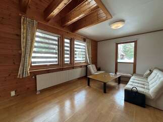 Experience cozy living in this charming wooden cabin, featuring a spacious living area with large windows offering scenic views.