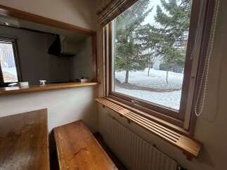 Enjoy the winter wonderland from this cozy dining area, featuring a pass-through window to the kitchen and a large window overlooking snow-covered trees.