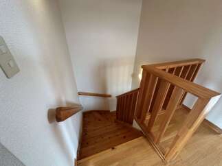 Ascend to the upper level via this charming wooden staircase, featuring a sturdy railing and a unique geometric design on the steps.