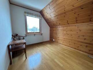 This charming room features a sloped wooden ceiling and walls, creating a cozy and rustic atmosphere.