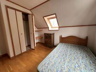 Discover this charming bedroom featuring a comfortable bed with a patterned mattress and a wooden headboard.