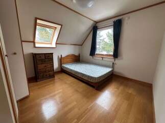 Discover this charming attic bedroom featuring a cozy wooden bed and a practical dresser, perfect for maximizing space.