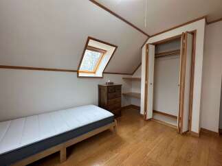 Discover this charming attic bedroom featuring a comfortable mattress on a wooden frame, perfect for a cozy retreat.