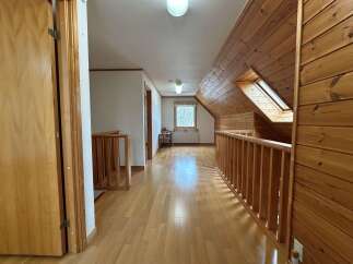 Step into this charming attic hallway featuring warm wooden paneling and a bright, airy atmosphere.