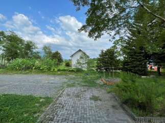 Discover this charming property featuring a cozy white house nestled amidst lush greenery and mature trees.
