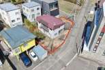 This aerial view showcases a residential property with a light gray exterior and a maroon roof, outlined by a red boundary.