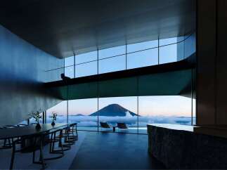Experience breathtaking panoramic views from this modern architectural marvel, featuring expansive floor-to-ceiling windows that showcase a majestic mountain peak above a sea of clouds.