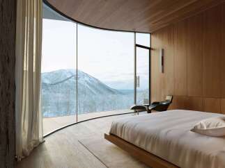 Experience breathtaking mountain views from this luxurious bedroom, featuring a stunning curved window that immerses you in the winter landscape.