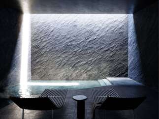 Experience ultimate relaxation in this modern spa oasis, featuring a serene indoor pool bathed in natural light from a dramatic skylight.