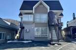 Discover this charming multi-story apartment building, featuring a modern gray and beige exterior with a dark pitched roof.