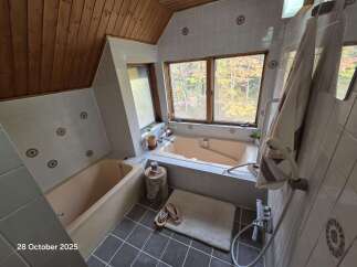 Experience ultimate relaxation in this charming bathroom featuring a spacious bathtub with a scenic view of autumn foliage.