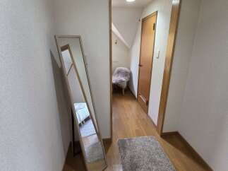Step into this charming hallway featuring a full-length mirror reflecting a cozy bedroom scene.