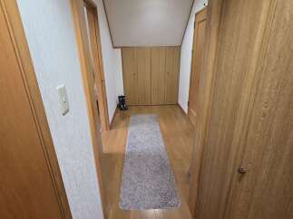 Step into this charming hallway featuring warm wooden floors and doors, creating a cozy and inviting atmosphere.
