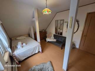 Discover this charming attic bedroom featuring a comfortable bed with fresh white linens and a decorative throw.