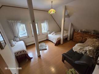 Discover this charming attic bedroom featuring two cozy single beds, perfect for guests or family.