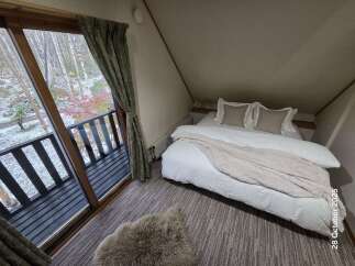 Experience cozy living in this charming attic bedroom, featuring a comfortable bed adorned with plush pillows and a soft throw blanket.