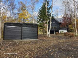 Experience the charm of autumn with this property featuring a modern black house nestled amidst vibrant fall foliage.