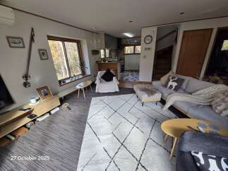 Experience cozy living in this inviting living room, featuring a comfortable grey sofa adorned with decorative pillows and a chunky knit throw.
