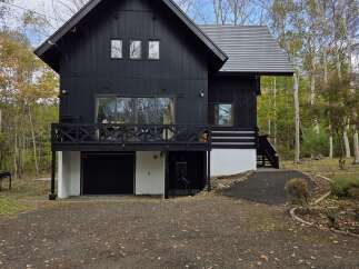 Discover this modern black home nestled amongst autumn trees, offering a striking architectural design.