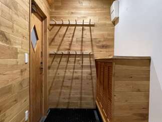 Step into a warm and inviting entryway featuring natural wood paneling and a charming wooden door with a diamond-shaped window.