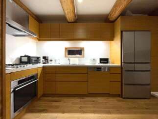 Experience modern living in this beautifully designed kitchen, featuring sleek wooden cabinetry and a full suite of stainless steel appliances, including a built-in oven and a spacious refrigerator.