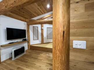 Experience rustic charm in this beautifully appointed room featuring exposed wooden beams and a natural wood accent wall.