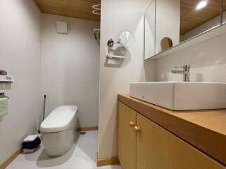 This modern bathroom features a sleek, wall-mounted toilet and a stylish rectangular vessel sink atop a warm wood vanity.