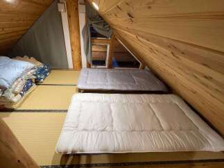 Discover this charming attic bedroom, featuring two comfortable futons laid out on traditional tatami mats.