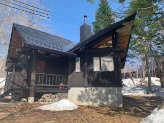 Experience rustic charm in this log cabin, featuring a dark wood exterior and a striking black metal roof.