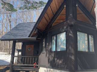 Discover this charming dark wood cabin nestled in a serene, wooded setting.
