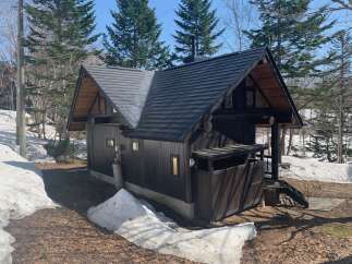 Discover this charming dark wood cabin nestled amidst a serene winter landscape.